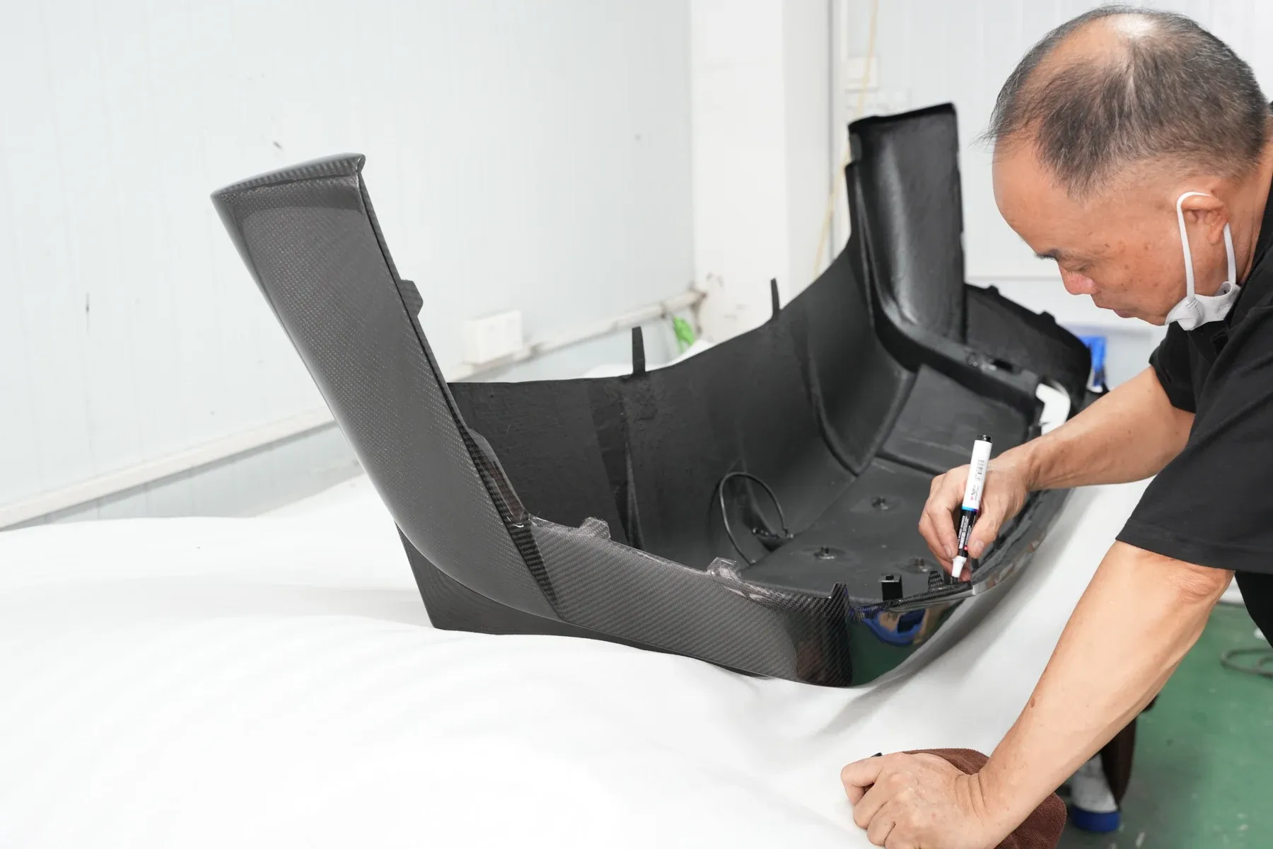 Technician marking a carbon aero part on the bench before refitting