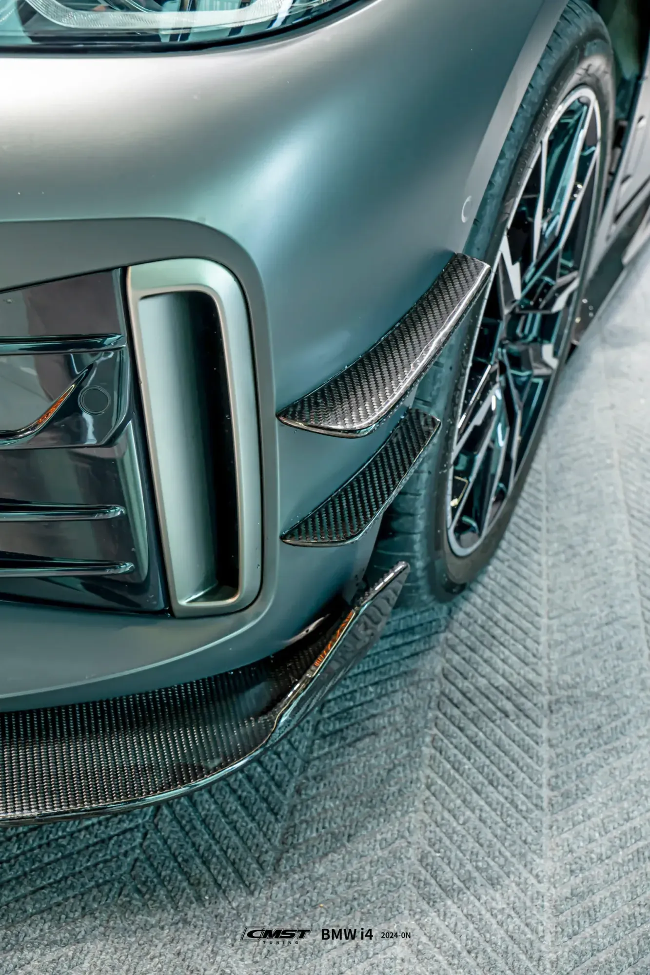 Carbon canards and a front lip fitted over the original bumper of a grey BMW i4