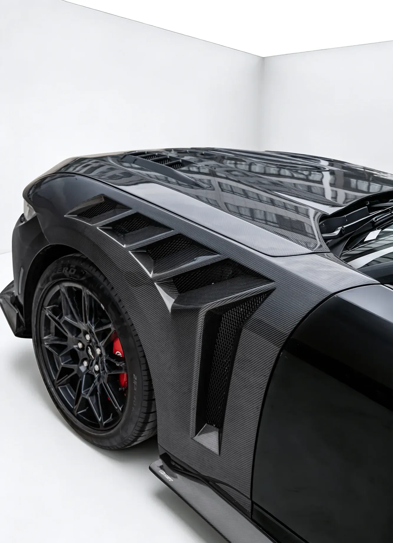 Carbon fiber wide front fenders with vented sections fitted to a black sports car