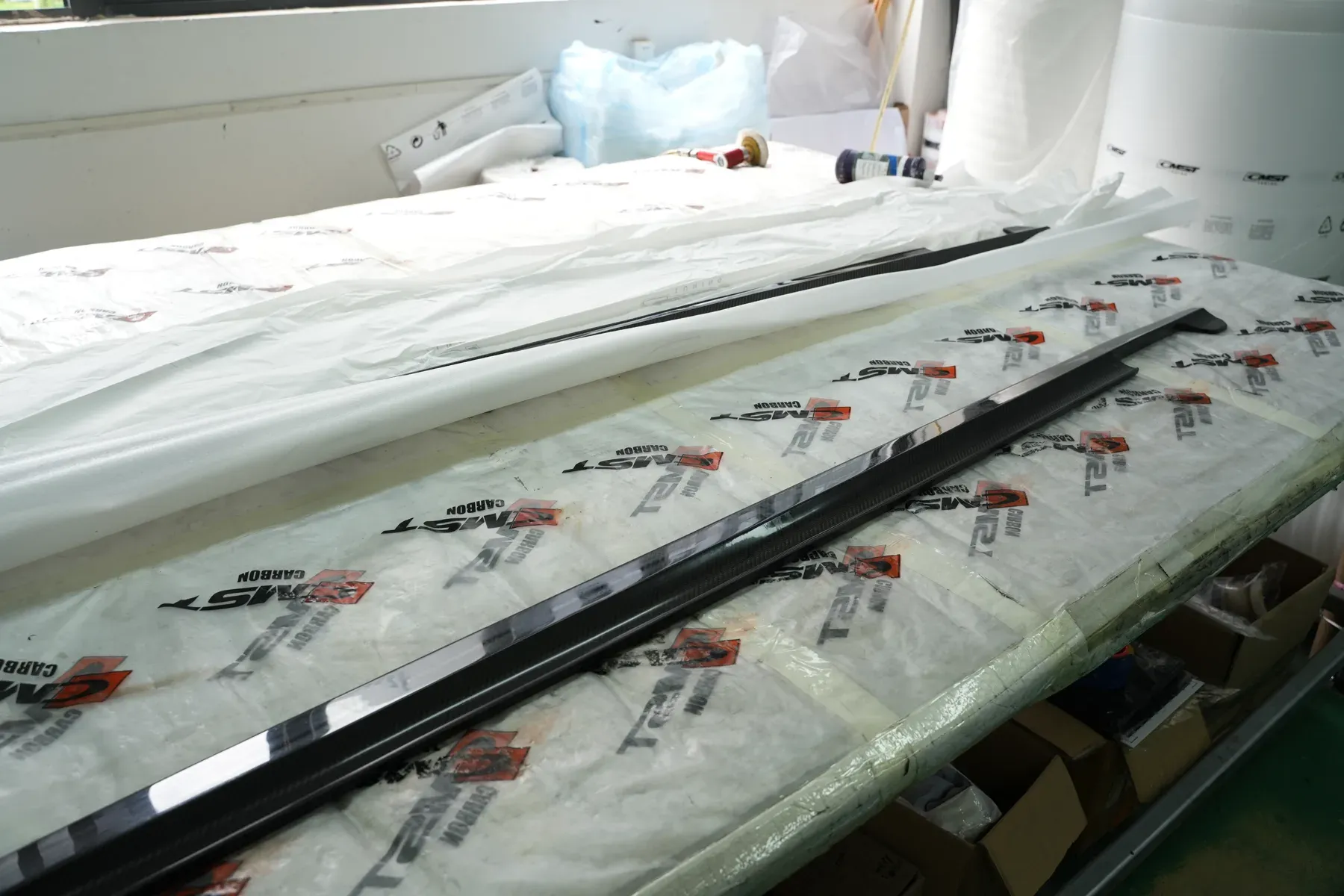CMST side skirts wrapped in branded protective film on a packing bench before shipping