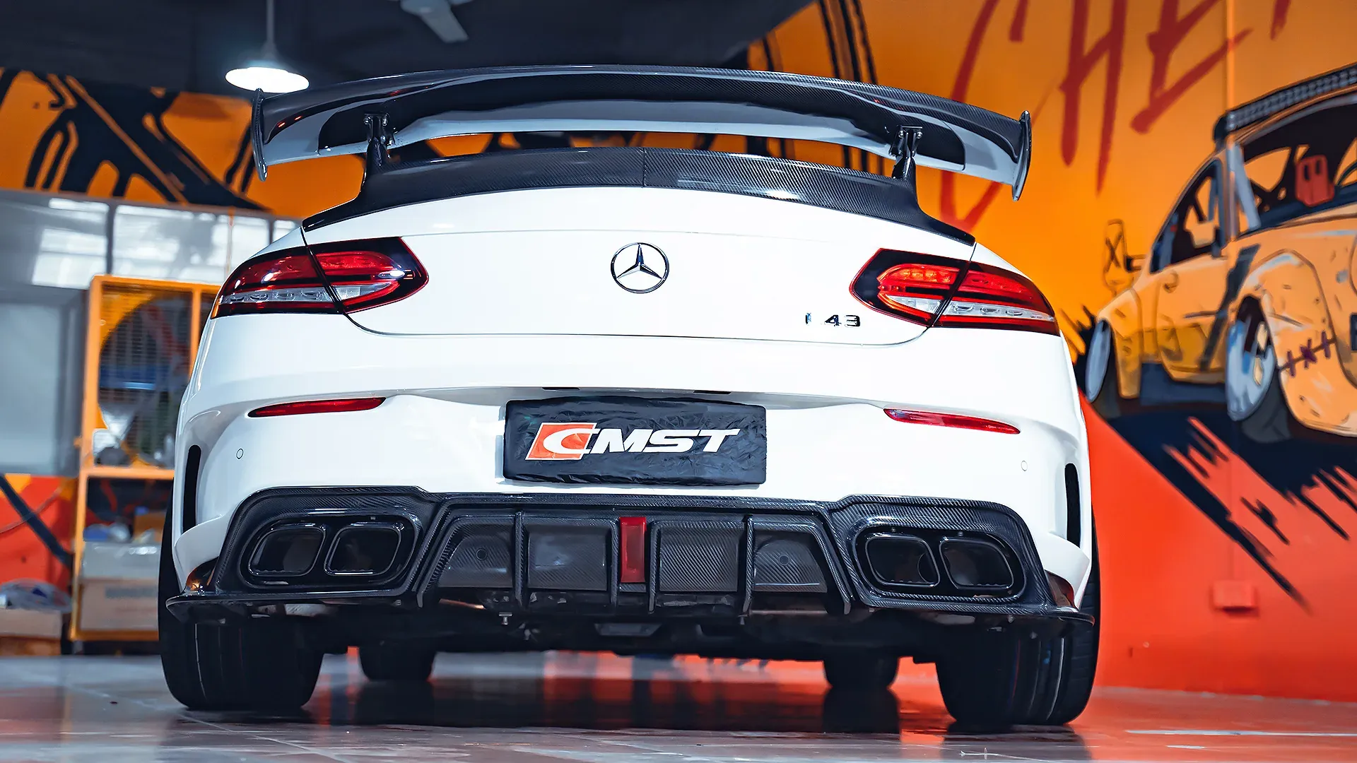 White Mercedes-AMG C43 coupe photographed from behind in a workshop, carbon rear wing, carbon diffuser and quad exhausts
