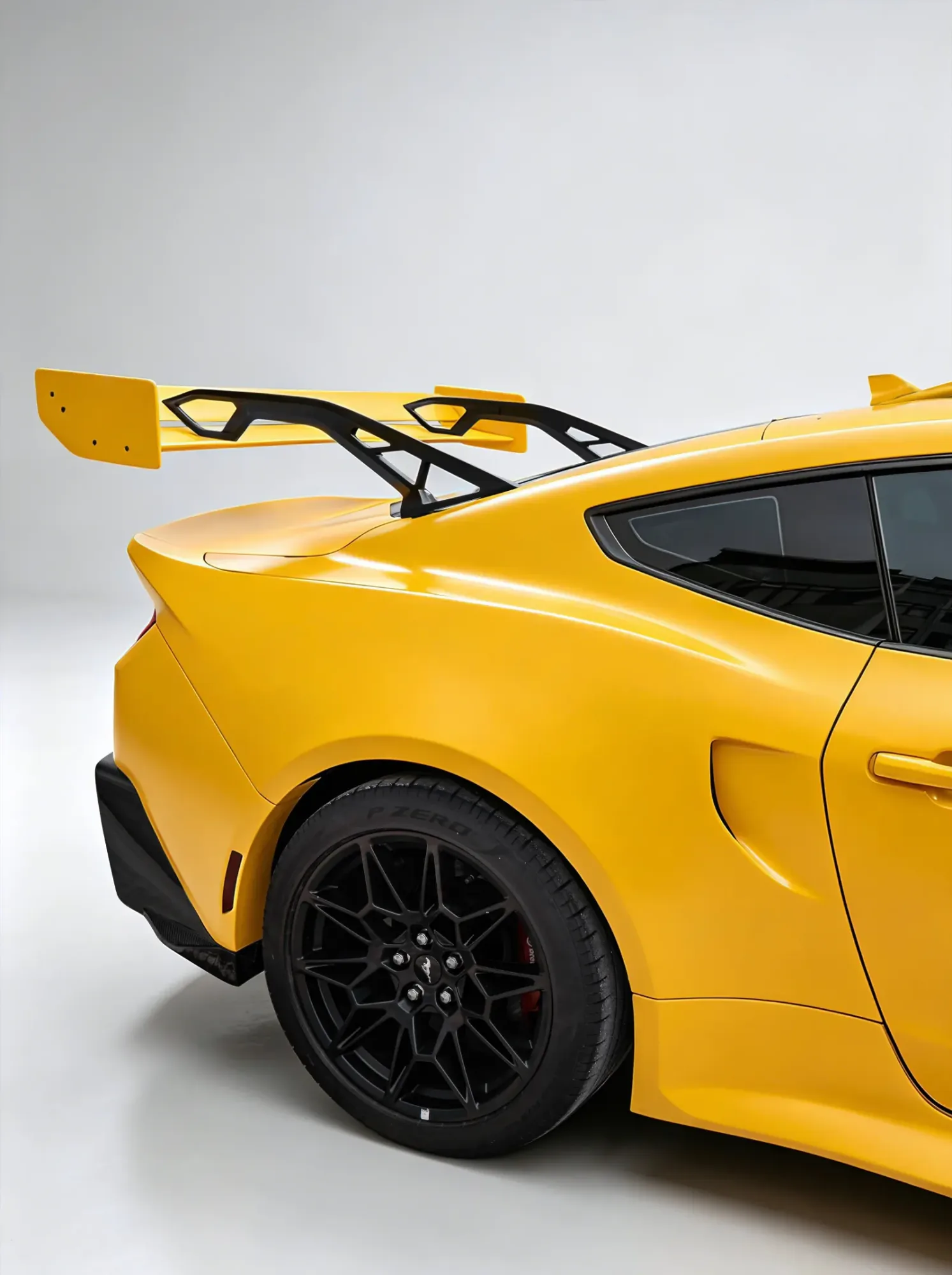 Yellow coupe seen from the rear three-quarter, showing a widened rear arch and a tall rear wing